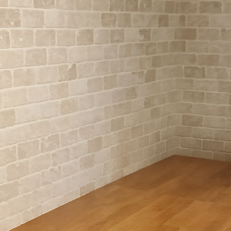 brick mosaic tiled wall A wall with light-coloured brick-patterned tiles and an iron on a dark surface below.