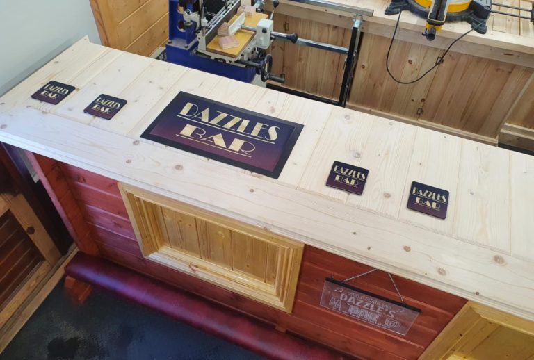 Wooden countertop featuring several signs, including "Dazzles Bar."