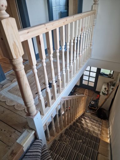 A view of a staircase with wooden banister and patterned runner, leading downwards.
