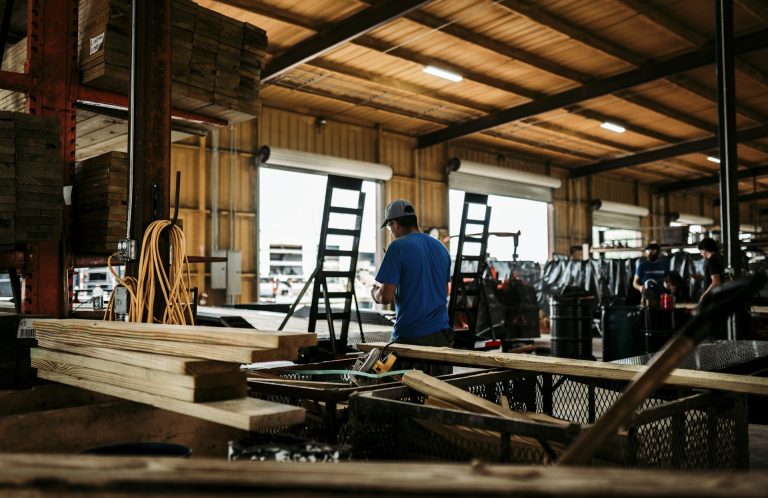 A person in a workshop setting surrounded by tools and wooden planks.
